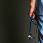Male doctor with stethoscope on dark background